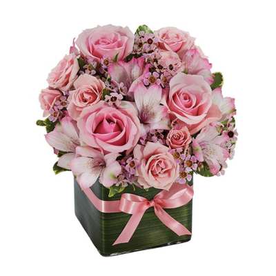 Pink roses and alstroemeria in a square vase with a pink ribbon
