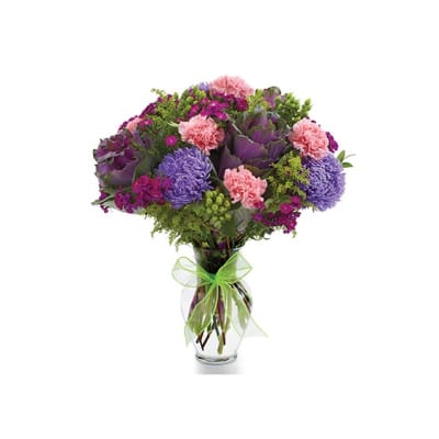 Mixed purple and pink bouquet in a clear glass vase with a green ribbon