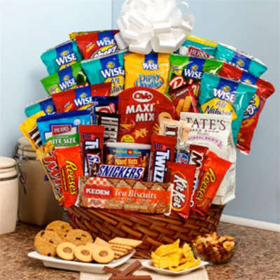 Basket filled with assorted snack bags and candy bars, with cookies and chips in front