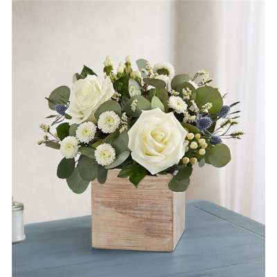 White roses and small white blooms in a wooden box vase