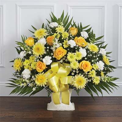 Yellow roses and daisies in a white standing arrangement with a yellow ribbon