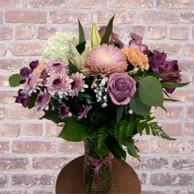 Mixed bouquet of pink, purple, and white flowers in a glass vase