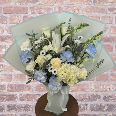Bouquet of white and blue flowers wrapped in pale blue paper