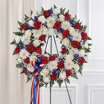 Circular standing wreath of red and white roses with white daisies and blue accents