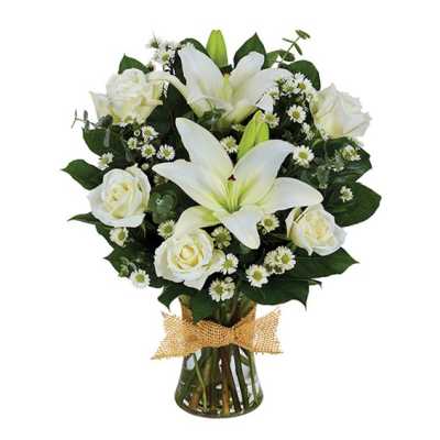 White lilies and roses in a glass vase with a burlap bow