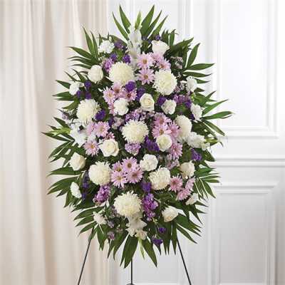 Standing floral spray with white, pink, and purple flowers on a tripod easel