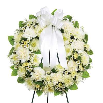 White floral wreath with a large white ribbon bow on an easel