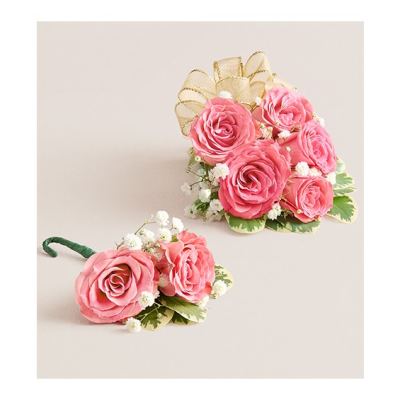 Pink rose corsage and boutonniere with white filler flowers and gold ribbon
