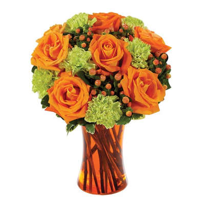 Orange roses and green carnations in an amber glass vase