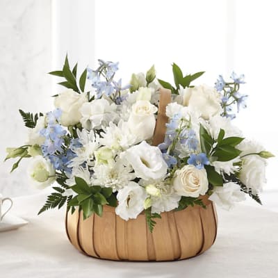 White and pale blue flower arrangement in a wooden basket