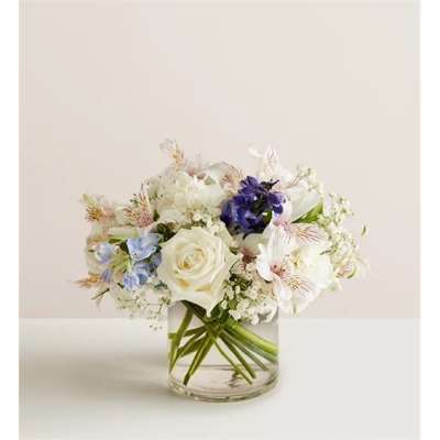 White rose and mixed pastel flowers arranged in a clear glass vase