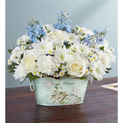 White roses and daisies with blue flowers in a decorative container