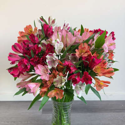 Mixed pink and orange flowers arranged in a clear glass vase