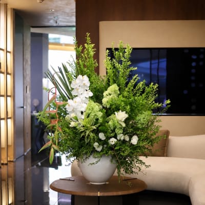 Large white and green floral arrangement in a round white vase