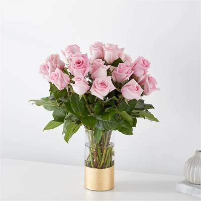 Arrangement of light pink roses in a clear glass vase with gold base