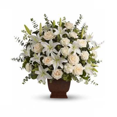 White lilies, cream roses, and carnations arranged in a large brown pedestal urn