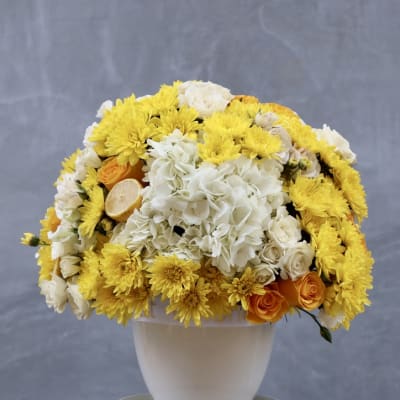 Yellow and white floral arrangement in a white vase