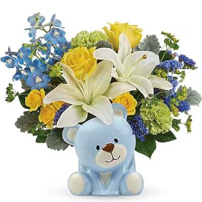 Blue teddy bear with a bouquet of white lilies, yellow roses, and blue flowers
