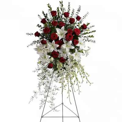 Standing floral spray with red roses and white lilies on an easel