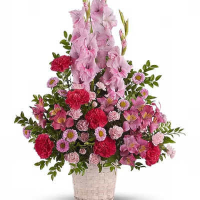 Pink and red mixed flower arrangement in a woven basket