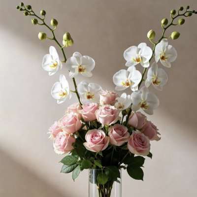 Pink roses and white orchids arranged in a clear glass vase.