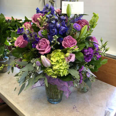 Mixed bouquet of purple, pink, and green flowers in a glass vase