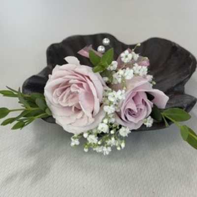Small boutonniere with pale pink roses and white baby's breath on a dark shell
