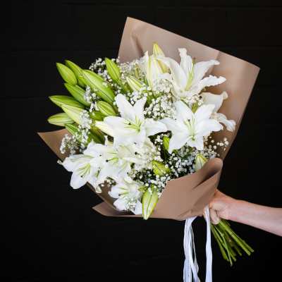 Bouquet of white lilies and baby's breath wrapped in brown paper