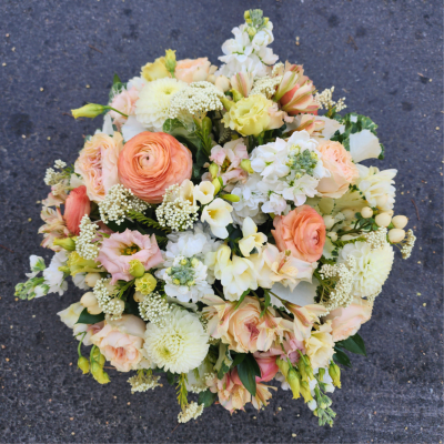 Round bouquet of peach, cream, and white flowers