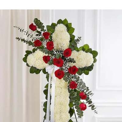 Standing floral cross with red roses and white blooms on an easel