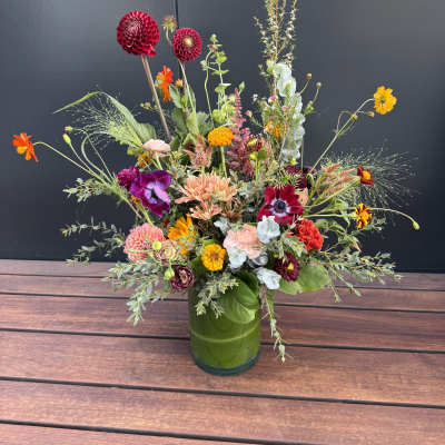 Colorful mixed flower arrangement in a green glass vase