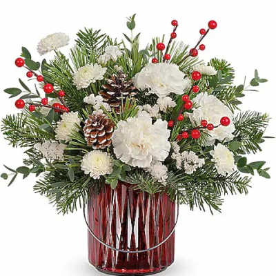 White flowers and pine arranged in a red glass vase with red berry accents