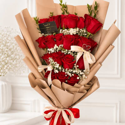 Bouquet of red roses wrapped in tan paper with ribbon