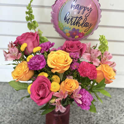 Pink and orange rose bouquet with a happy birthday balloon in a vase