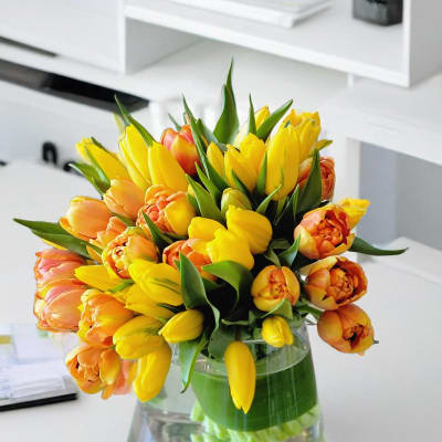 Yellow and orange tulips arranged in a clear glass vase