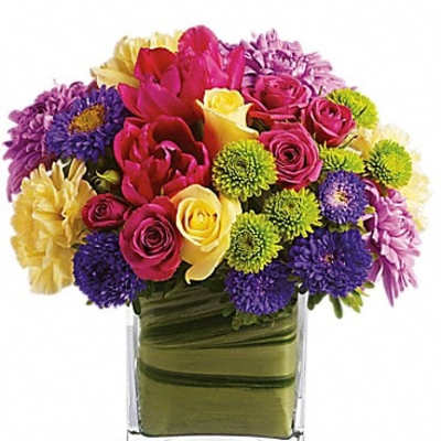 Colorful bouquet of mixed flowers in a clear square vase