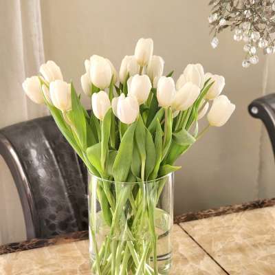 White tulips in a clear glass vase on a table