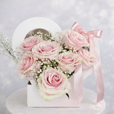 Pink roses arranged in a white gift box with a pink ribbon