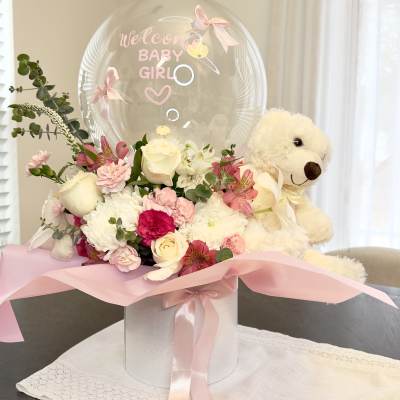 Pink and white flower arrangement with a teddy bear and "Welcome Baby Girl" balloon