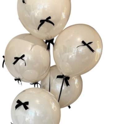 Cluster of cream balloons with black bows and a black ribbon tail