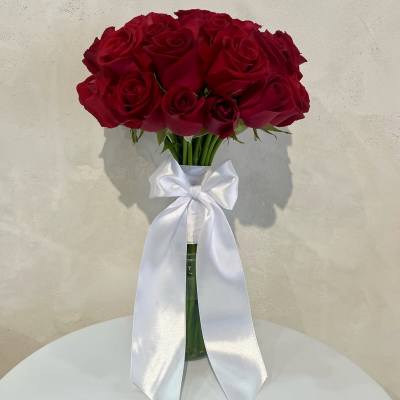 Bouquet of red roses in a glass vase with a white ribbon bow