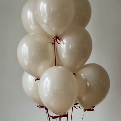 Cluster of cream-colored balloons tied with red ribbons