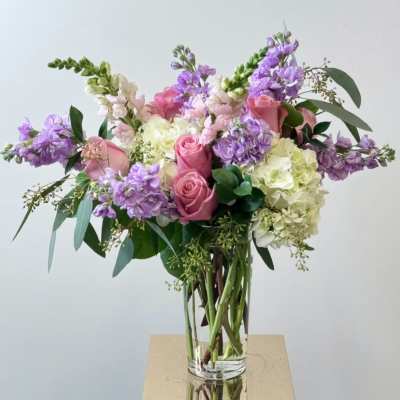 Pink roses and purple flowers in a clear glass vase