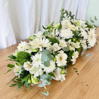 White floral arrangement with daisies and lilies on a wooden table