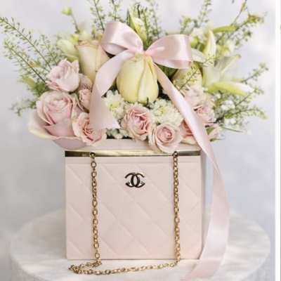 Pink and white flowers arranged in a pale pink box with a ribbon bow