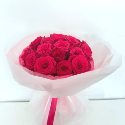 Bouquet of bright pink roses wrapped in pale pink paper