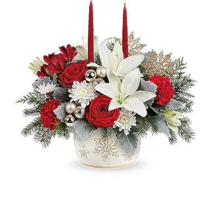 Holiday arrangement with red roses, white lilies, and two red candles in a snowflake vase