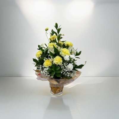 Arrangement of yellow and white carnations with baby's breath in a wrapped glass vase