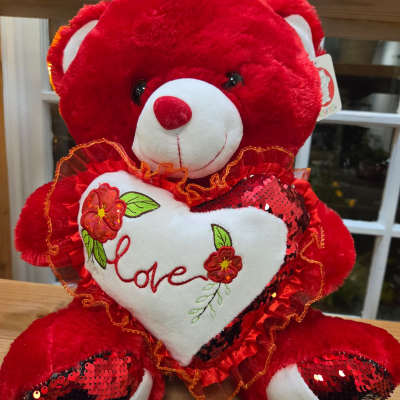 Red teddy bear holding a white heart with the word love