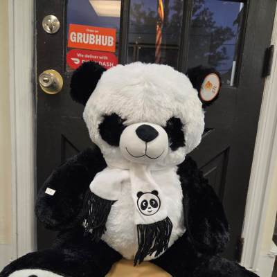 Large black-and-white panda plush toy sitting on a stool